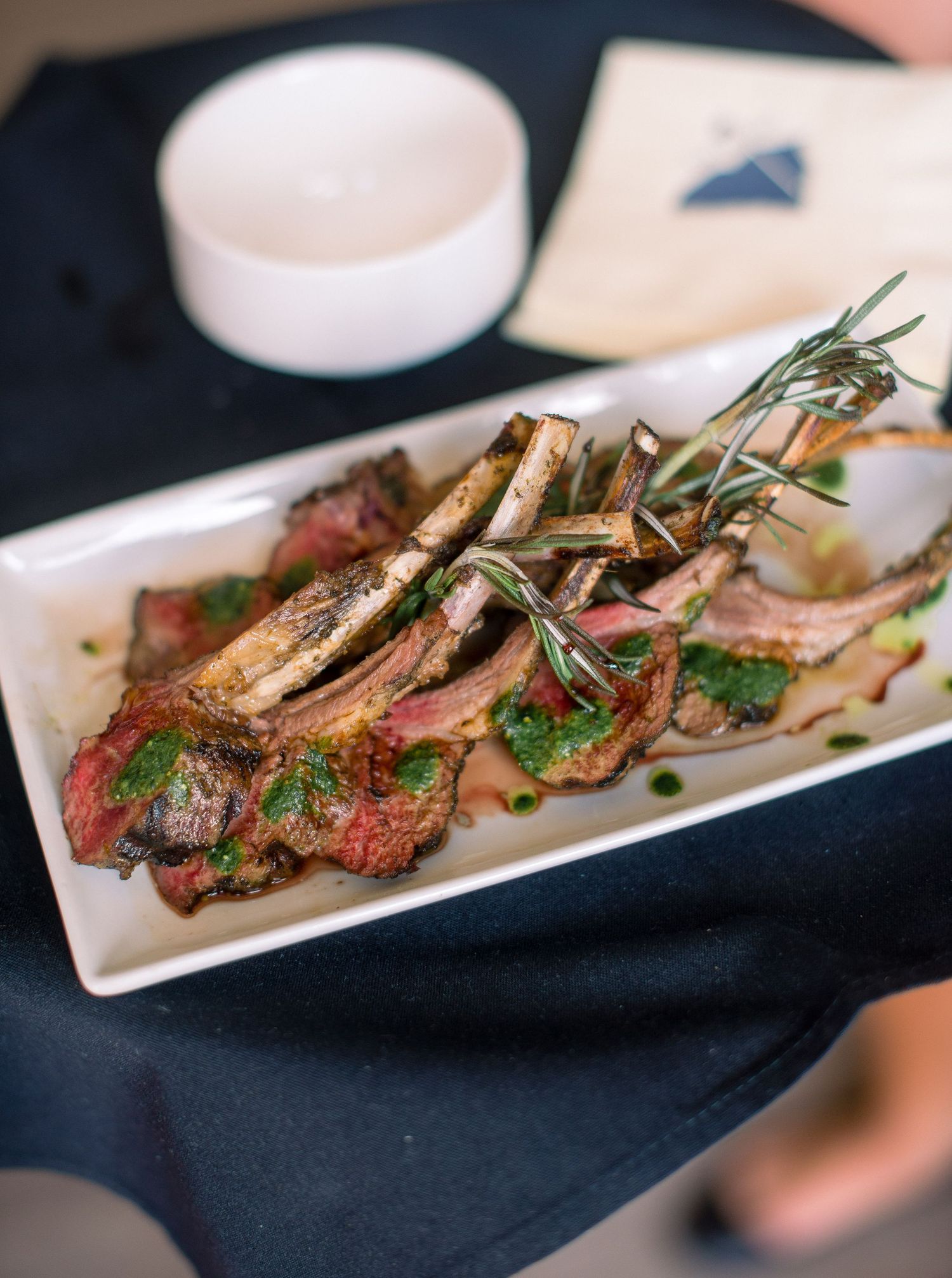 Grilled steak slices garnished with fresh rosemary and herbs served on white rectangular plates.