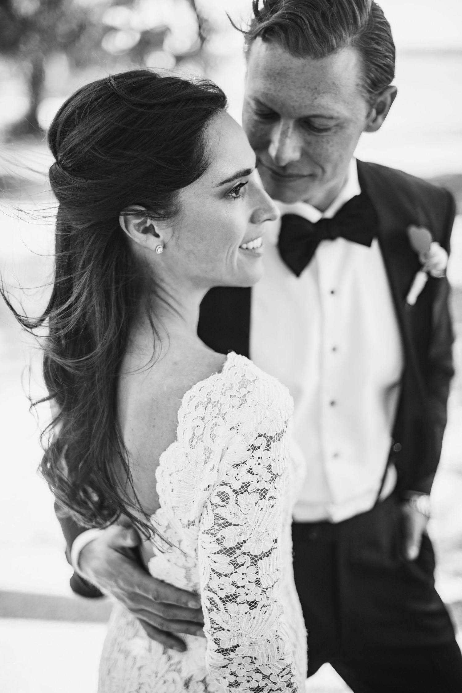 A romantic black and white photo series of a bride and groom sharing intimate moments in their wedding attire.