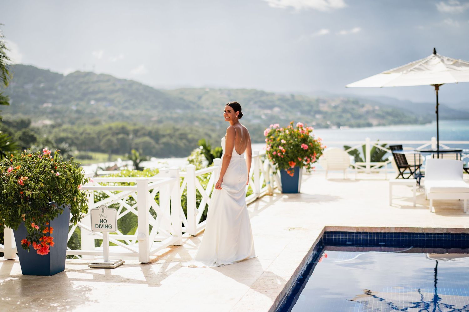 A scenic panoramic view of a luxury destination wedding venue with white decor overlooking mountains and water.