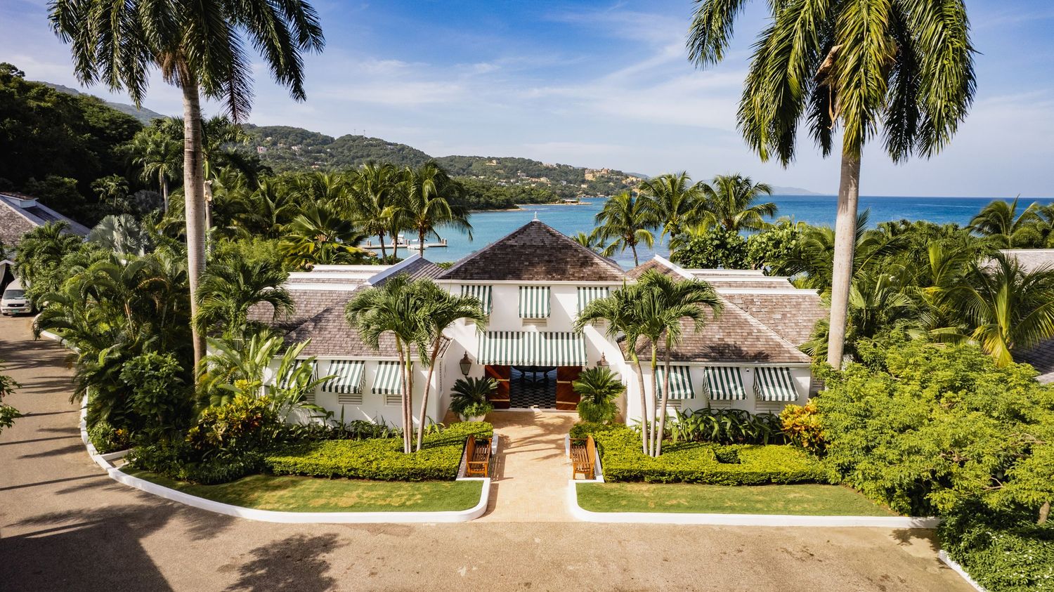 Panoramic view of a tropical residential neighborhood with palm trees and luxury homes under bright blue skies.