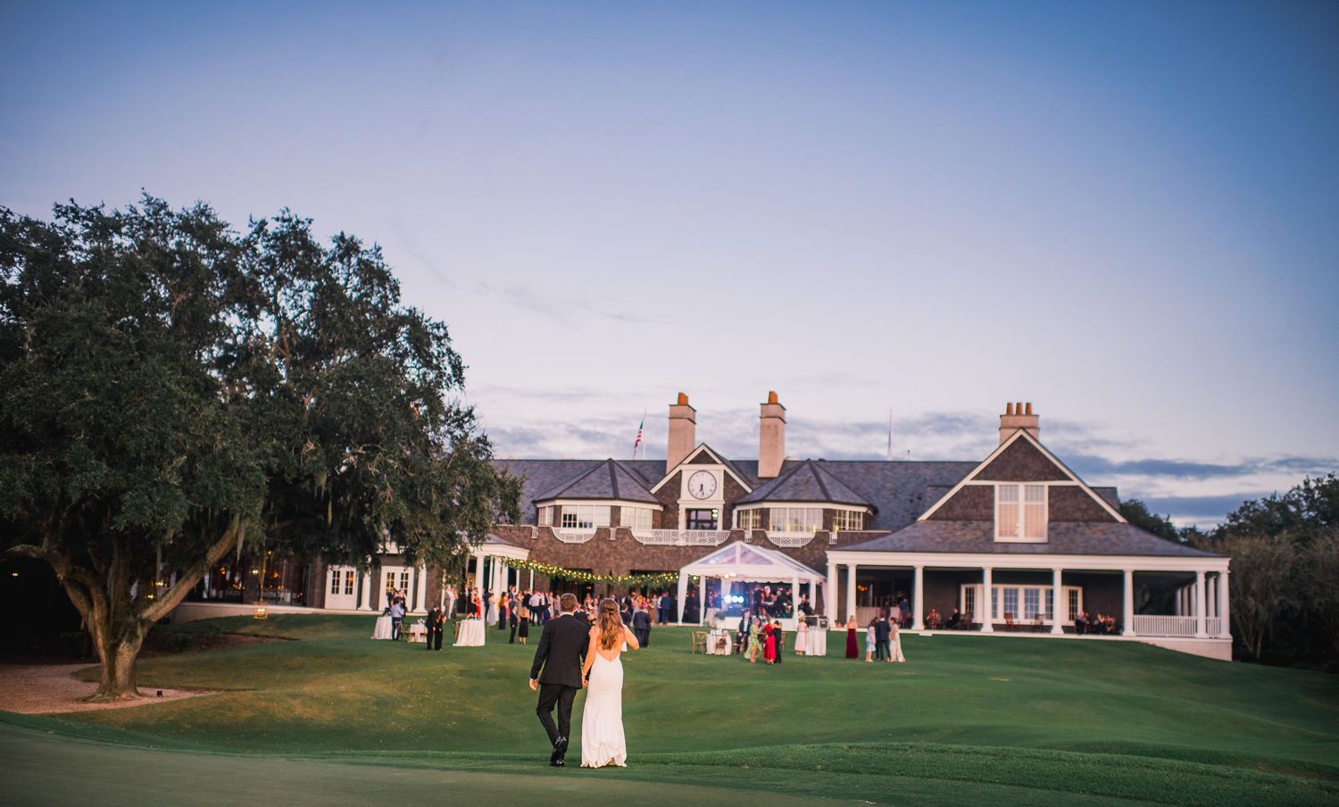 A scenic outdoor wedding venue with elegant white buildings and manicured lawns under a blue sky.