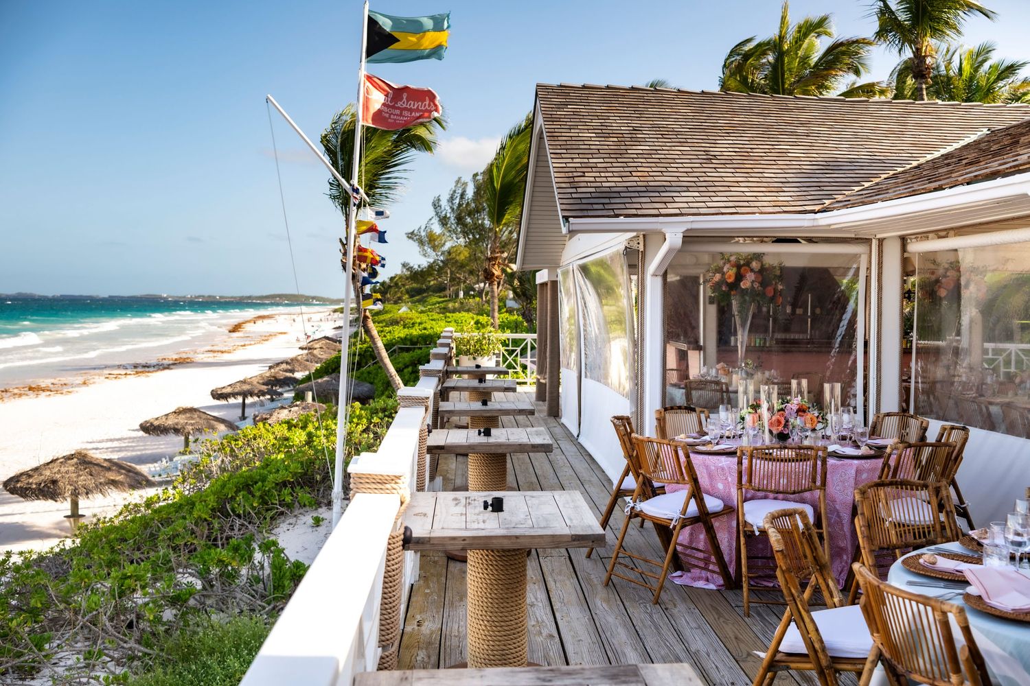 Beachfront restaurant terrace with wooden deck, palm trees, and ocean views at the tropical Coral Sands hotel and resort