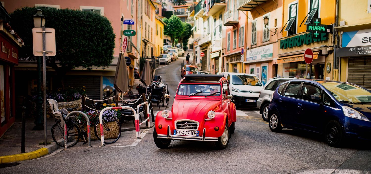 Colorful vintage cars parked along a narrow street in beaulieu sur mer with historic buildings in warm Mediterranean tones.