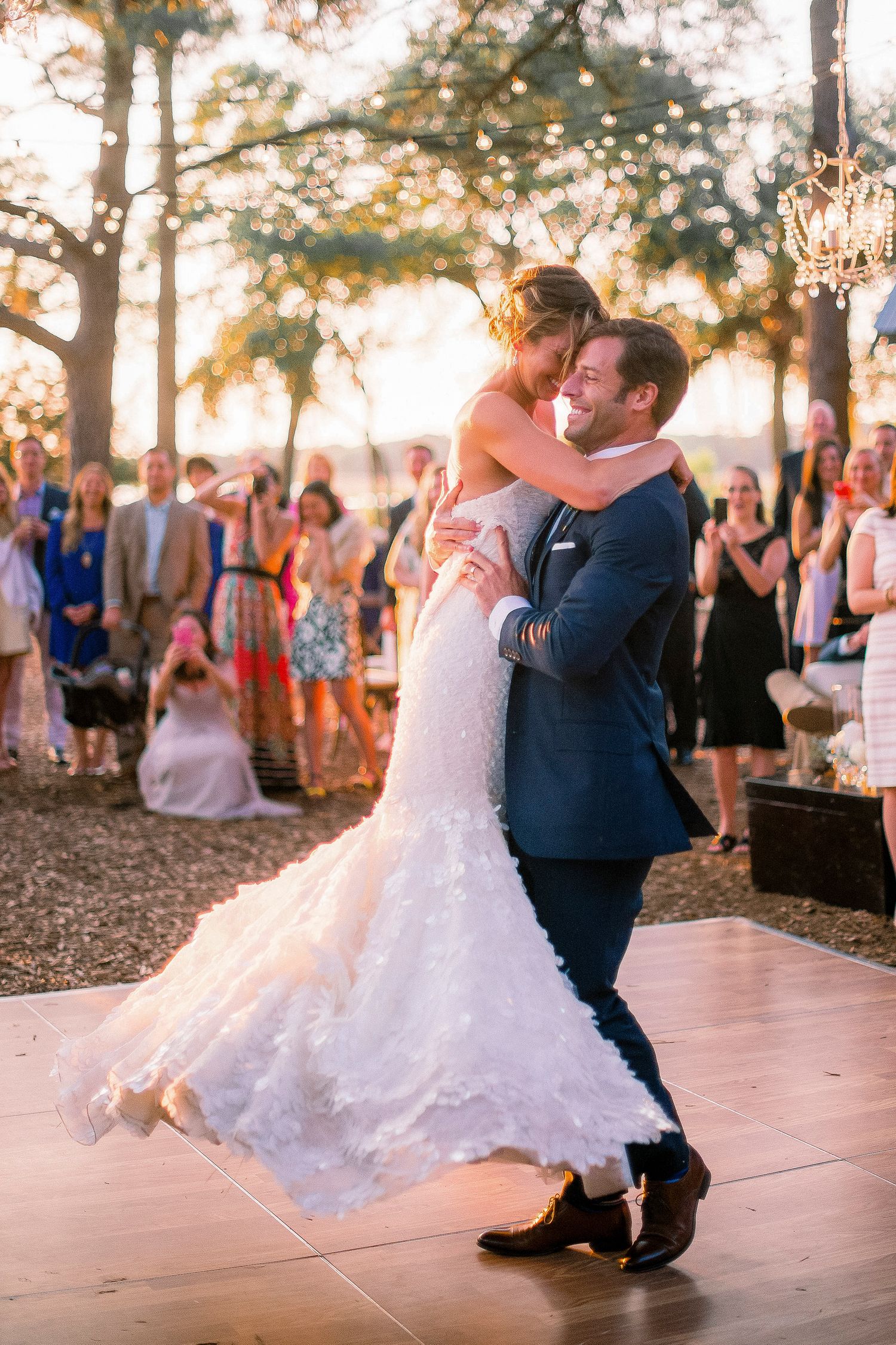 Couple shares romantic first dance at outdoor sunset wedding reception.