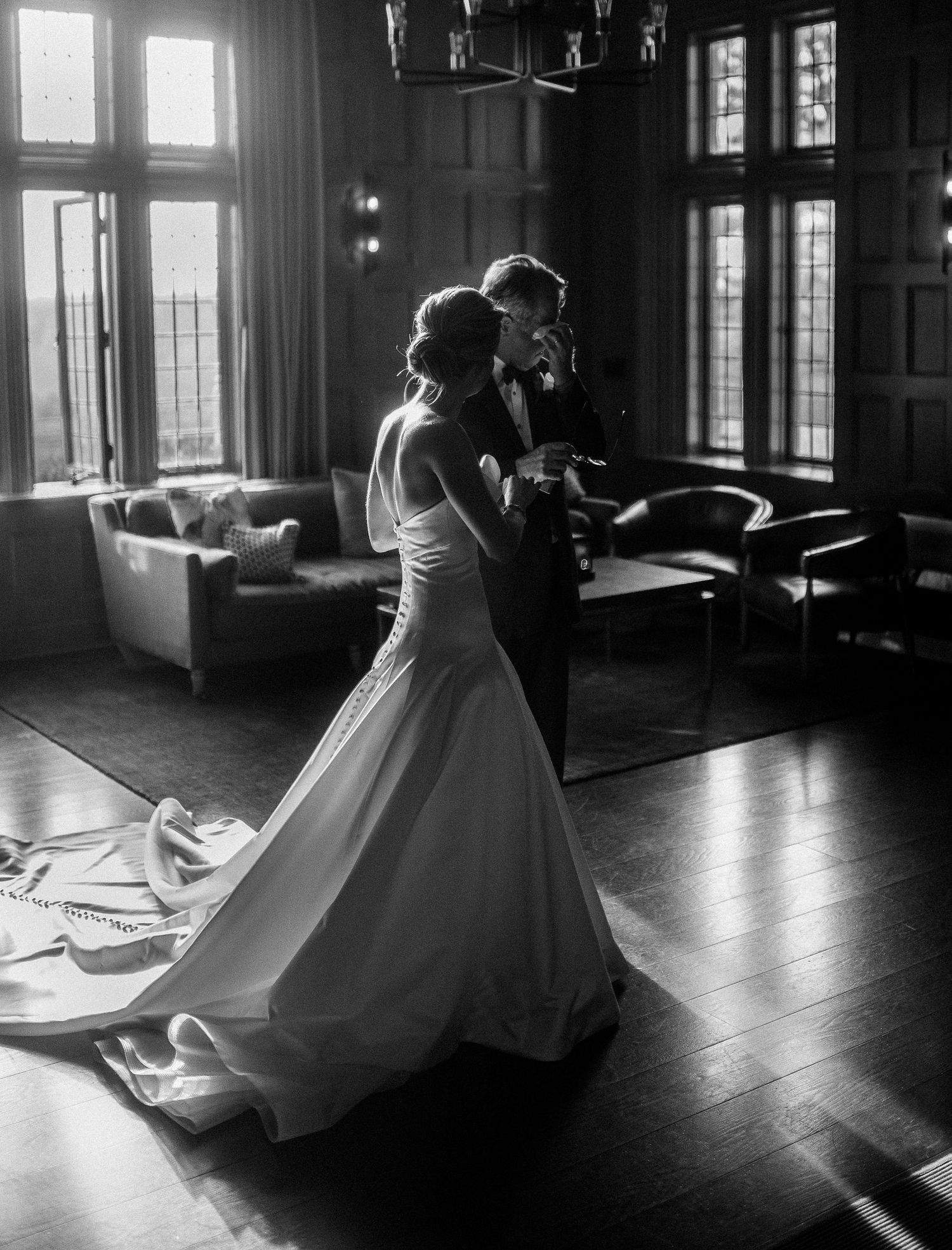 Silhouetted couple dancing in sunlit ballroom with dramatic window lighting creating romantic atmosphere.