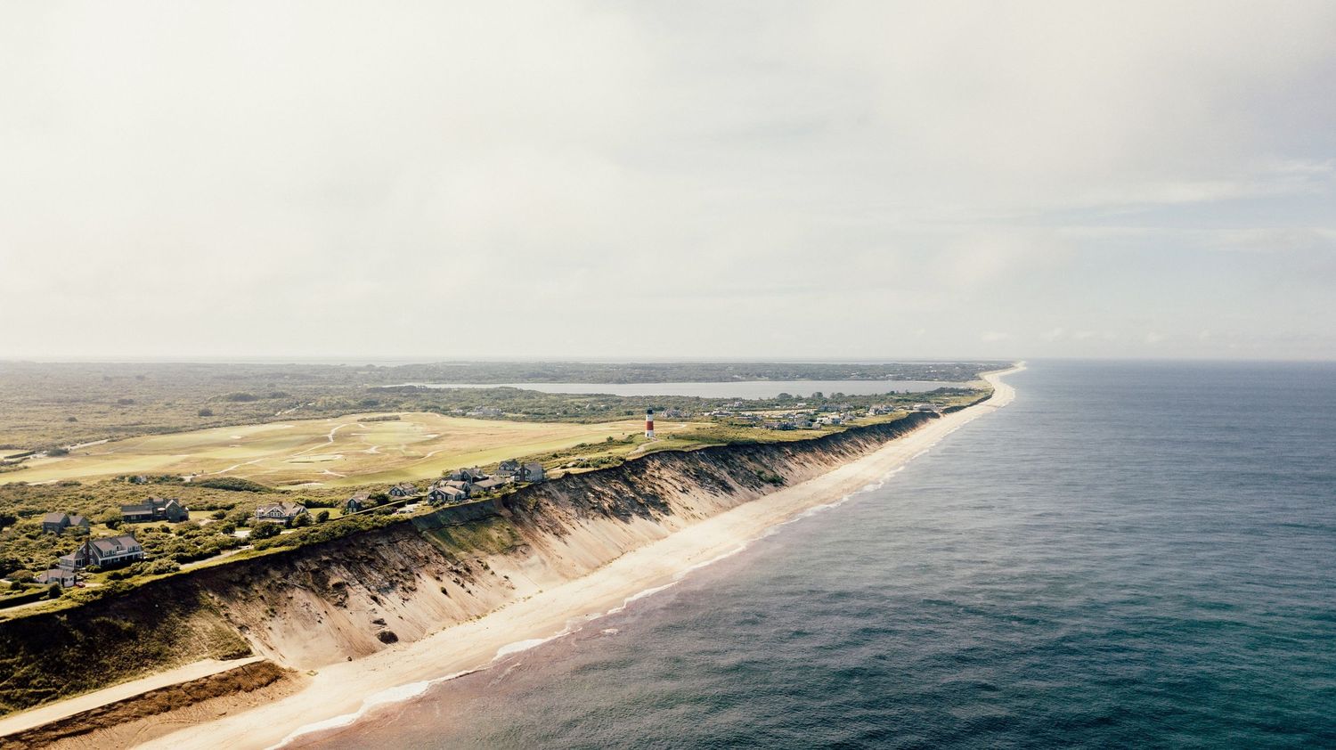 Aerial panoramic view of a pristine coastline in Nantucket with sandy beaches stretching into the distance.