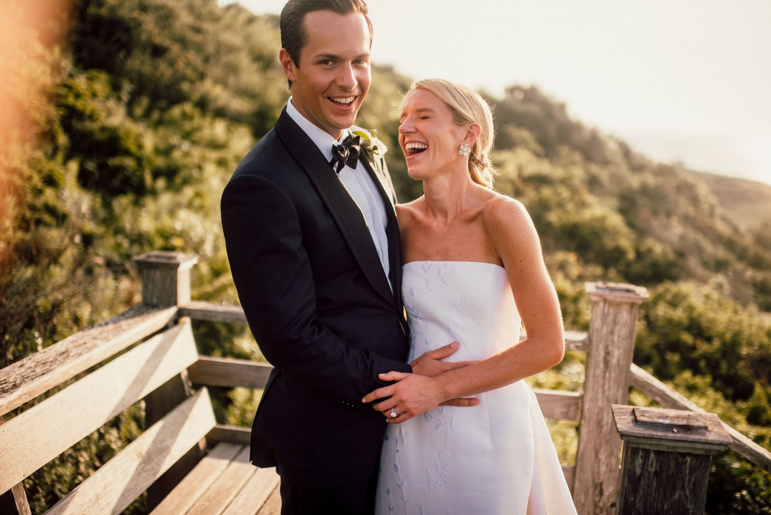 A romantic wedding photo session on a scenic overlook with mountains in the background.