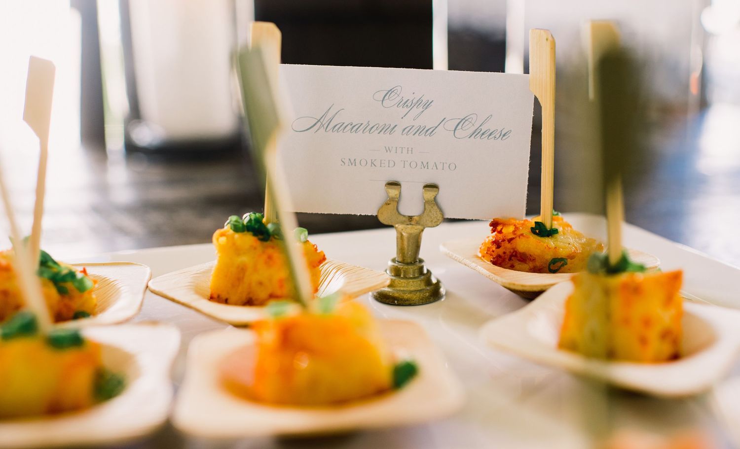 Elegant appetizer plates arranged with golden-colored bites and a small decorative wedding topper centerpiece.