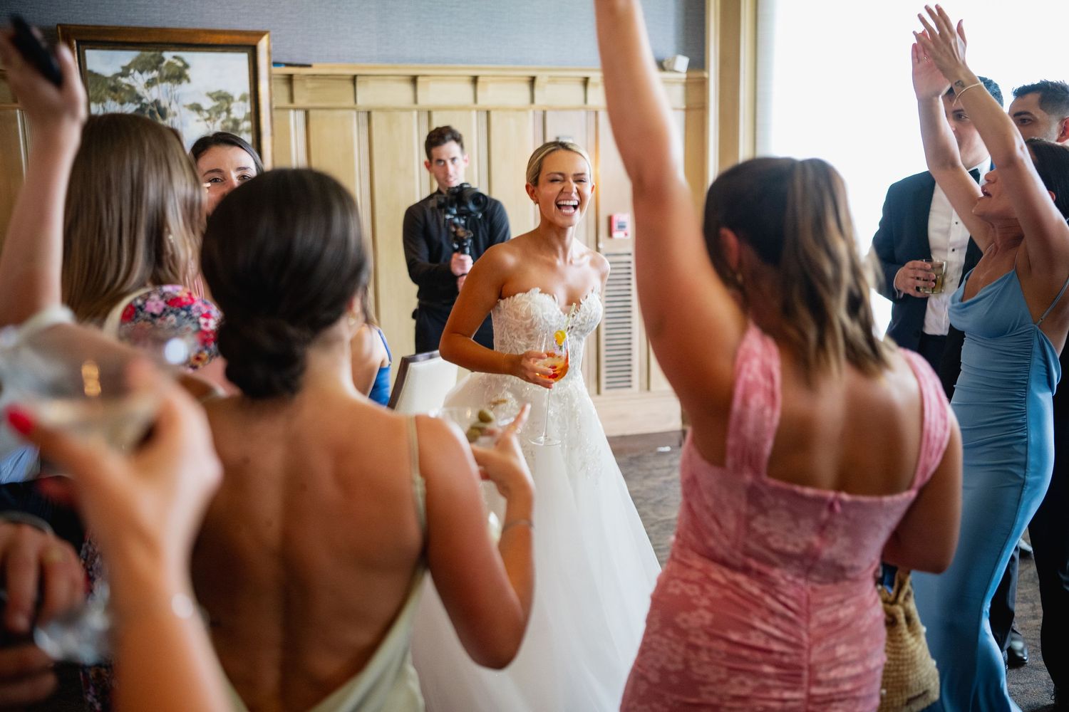Wedding reception guests dancing with raised arms in celebration.