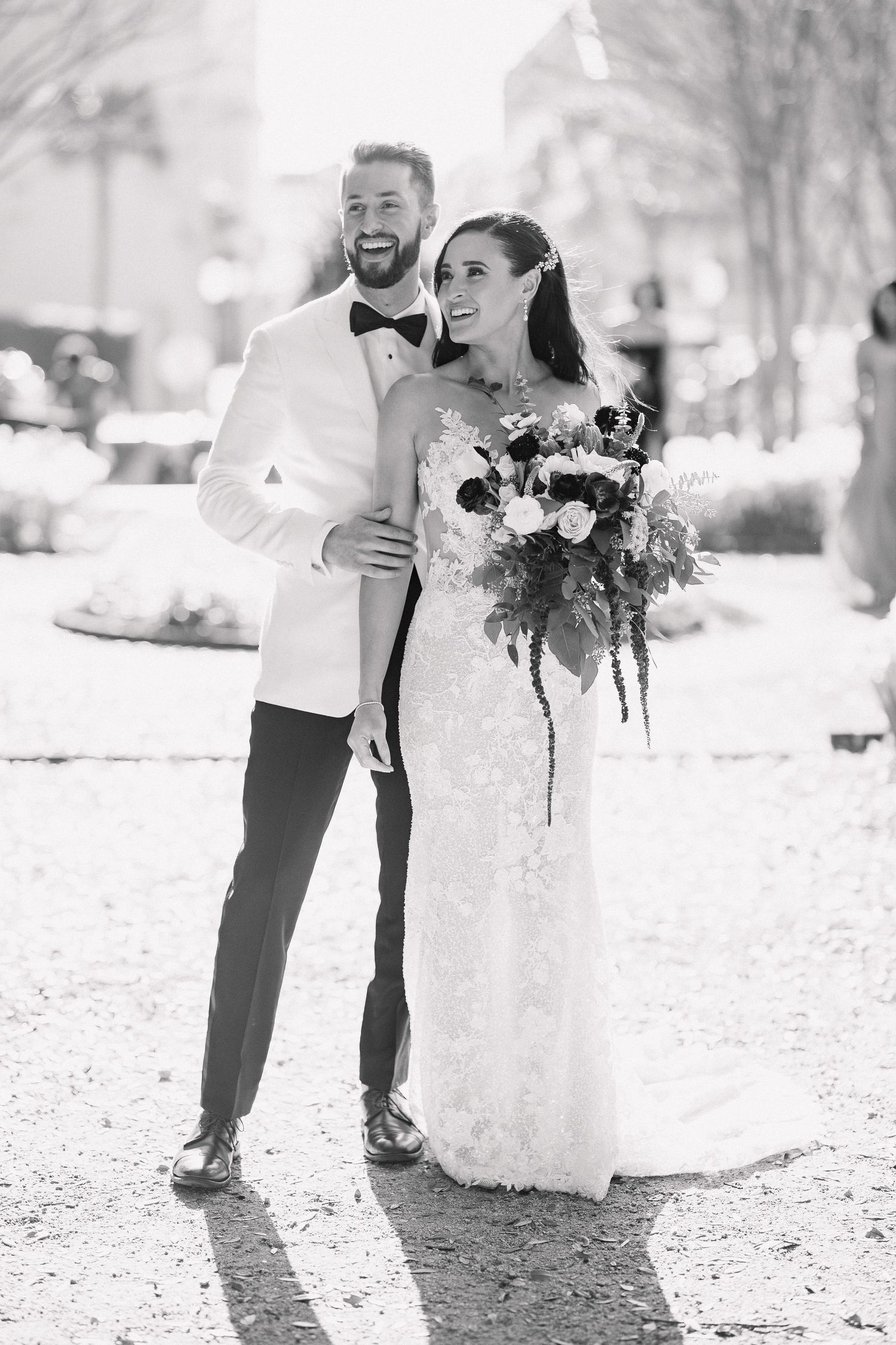A couple in wedding attire shares a romantic moment in a snowy winter setting with white florals.