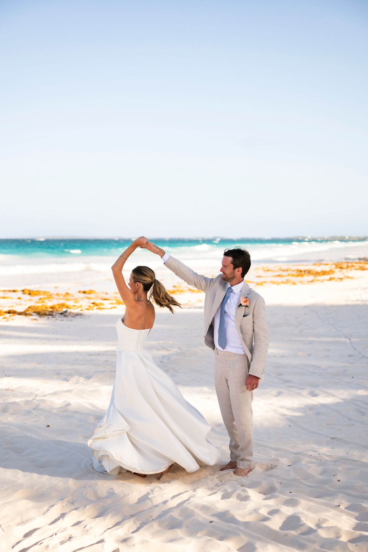 Romantic beach wedding photos with couple posing on white sand near turquoise waters.