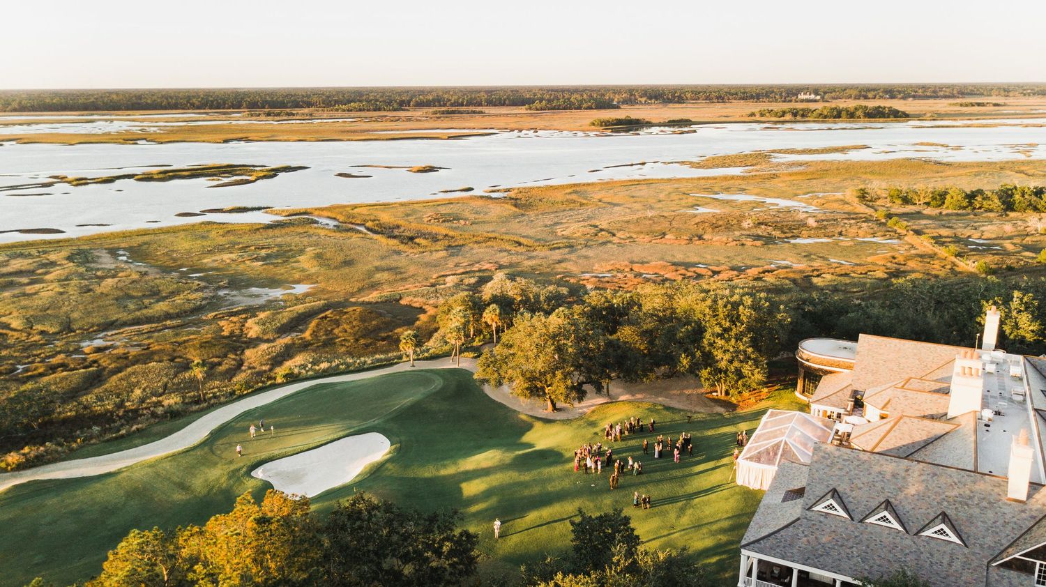 Scenic aerial view of a coastal golf course with rolling fairways and sand traps during golden hour.