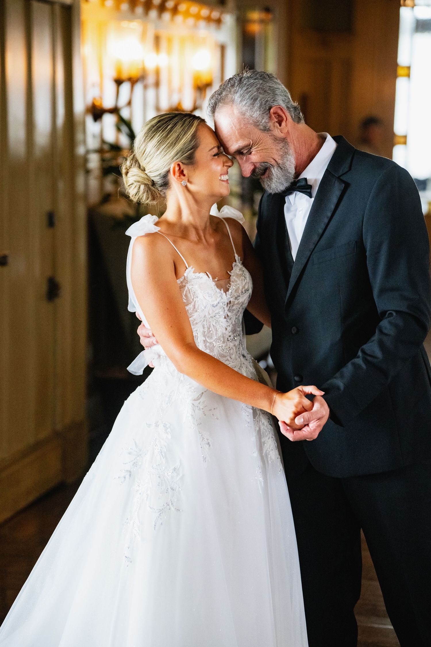 Intimate wedding moment captured in an elegant indoor hallway with warm lighting and romantic atmosphere.