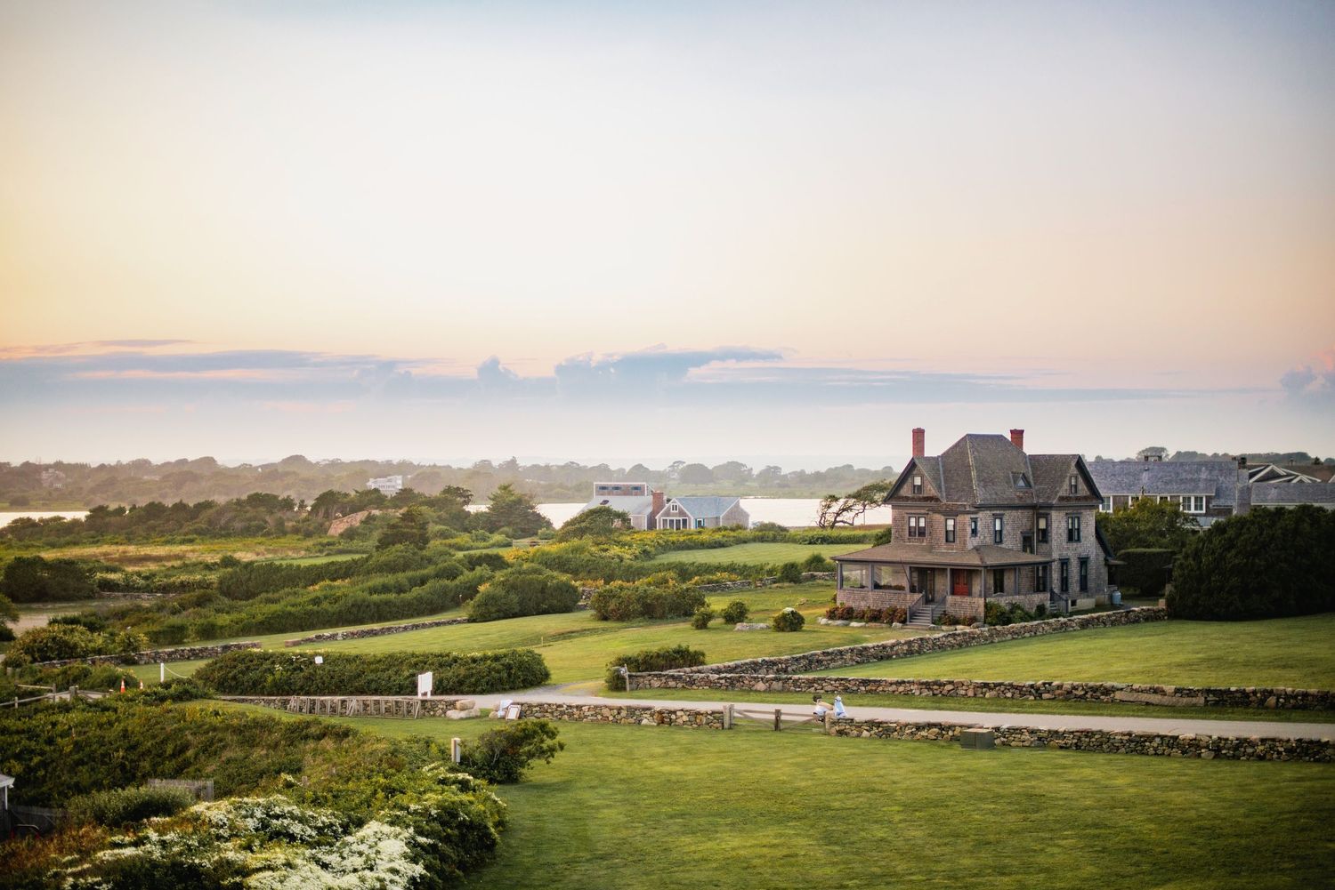 Coastal golf course landscape with rolling green hills and oceanfront luxury homes in Little Compton RI