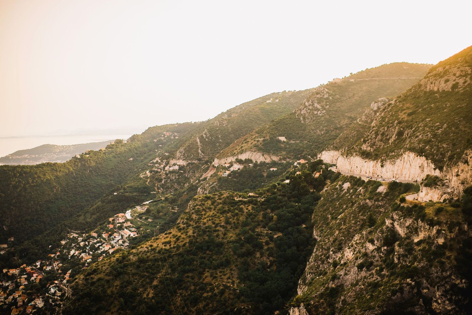 Golden sunlit mountainside with rocky cliffs and scattered vegetation in warm evening light.