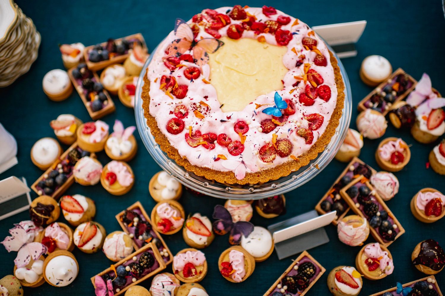 Elegant dessert display featuring cream puffs and a decorated cake topped with fresh red berries.