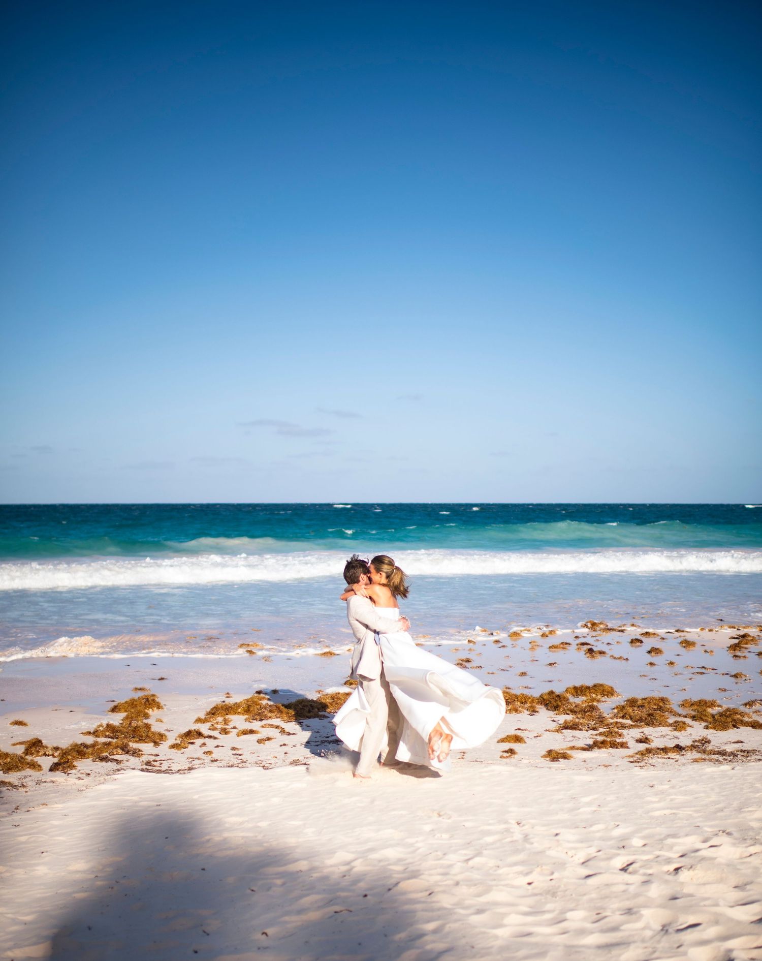 Couple embracing on a scenic beach with turquoise waters and white sand.