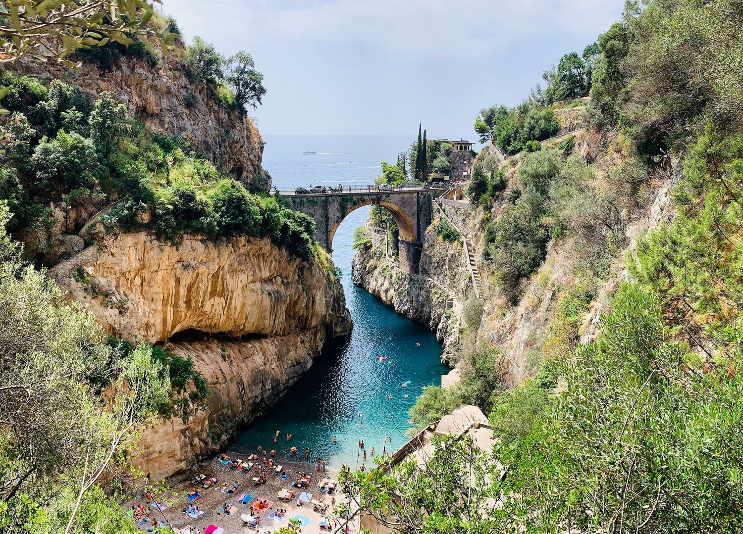 Stunning natural arch bridge over turquoise waters at the Fiordo di Furore on Italy's Amalfi Coast.