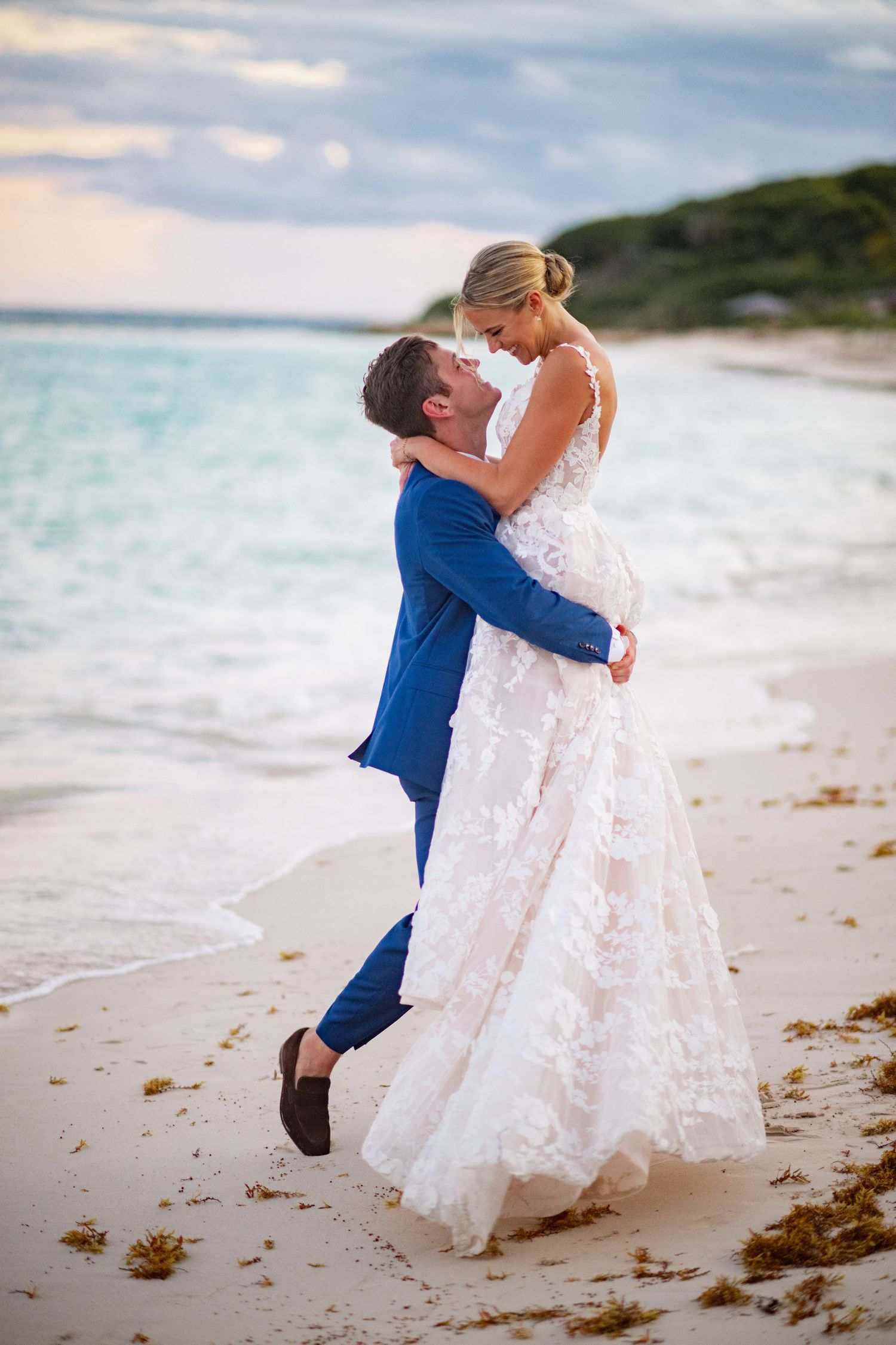 A romantic beach photoshoot featuring a flowing white wedding dress against turquoise waters.