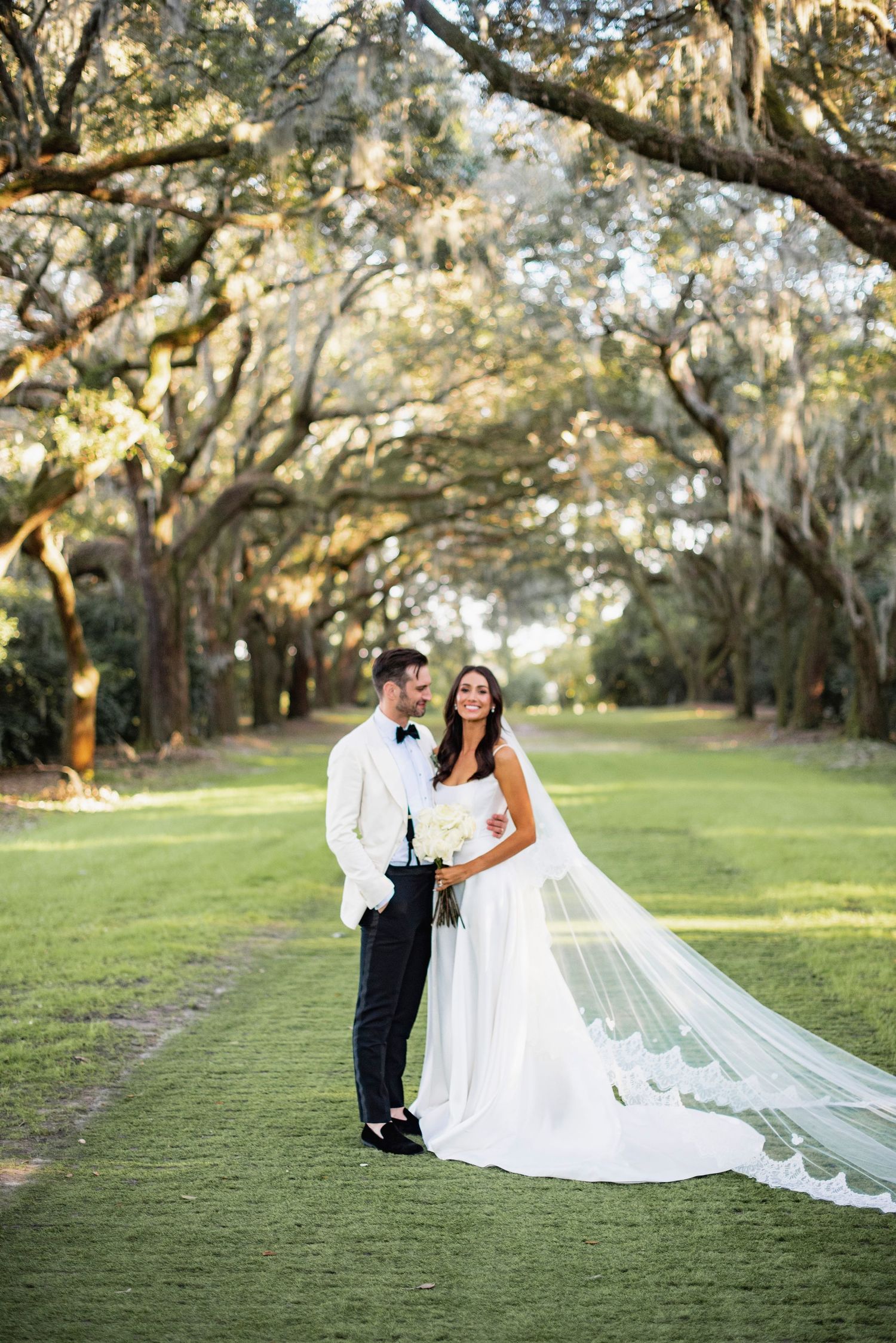 Beautiful wedding portraits taken under majestic oak trees draped with Spanish moss in a serene garden setting.