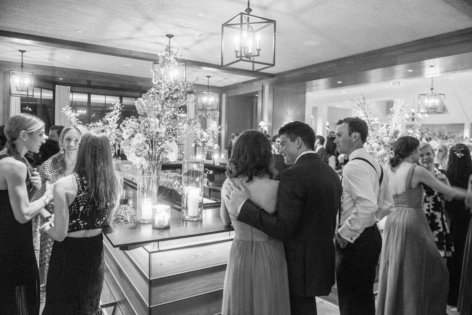 Elegant black and white wedding reception photo showing guests gathered around a beautifully lit display at an evening event.