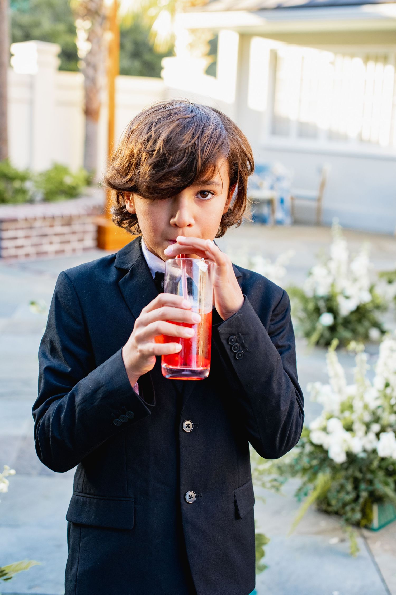 A sequence of four photos showing someone in a black blazer drinking from a glass against a light outdoor background.