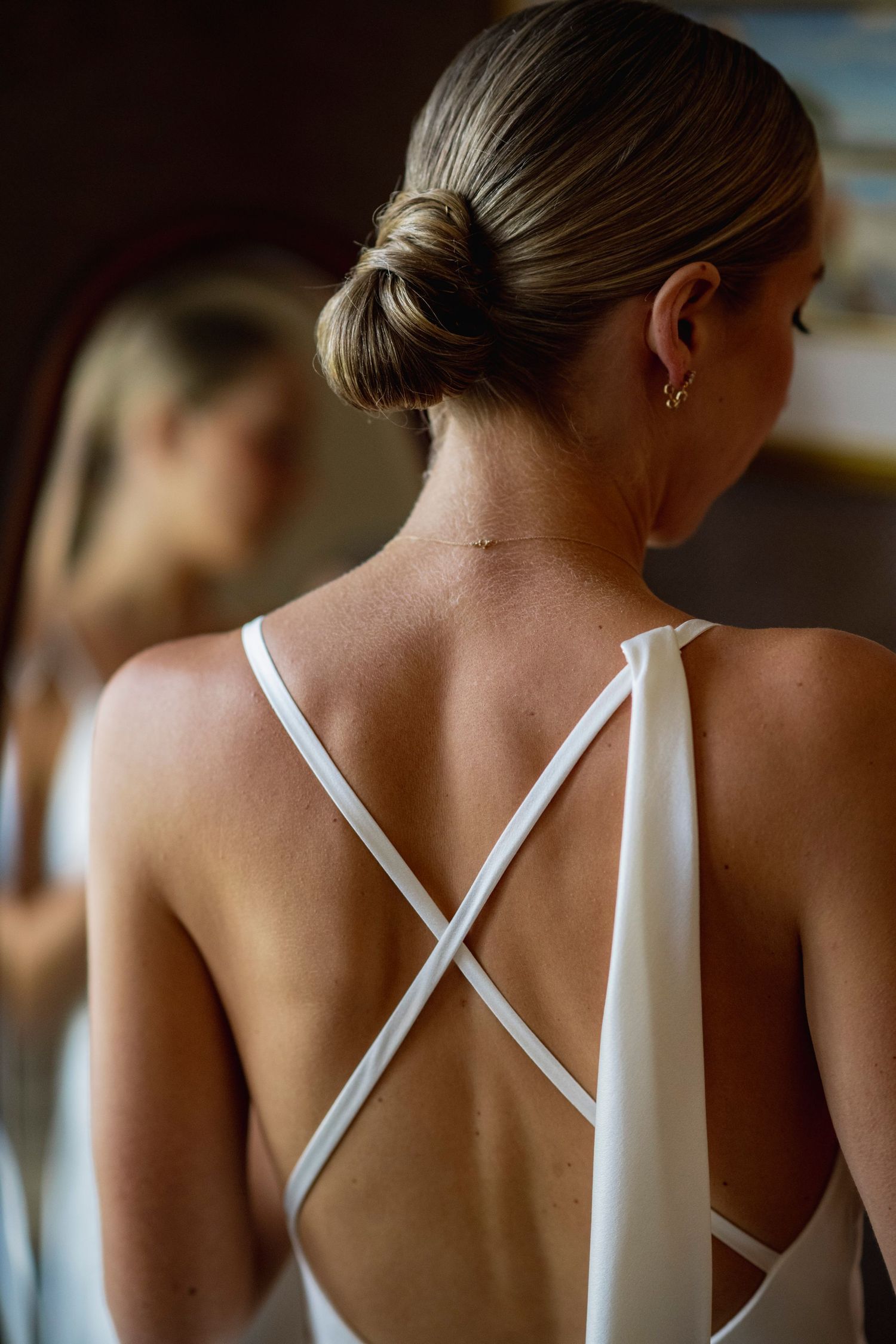 Elegant white cross-back wedding dress detail shown from behind with sleek updo hairstyle.