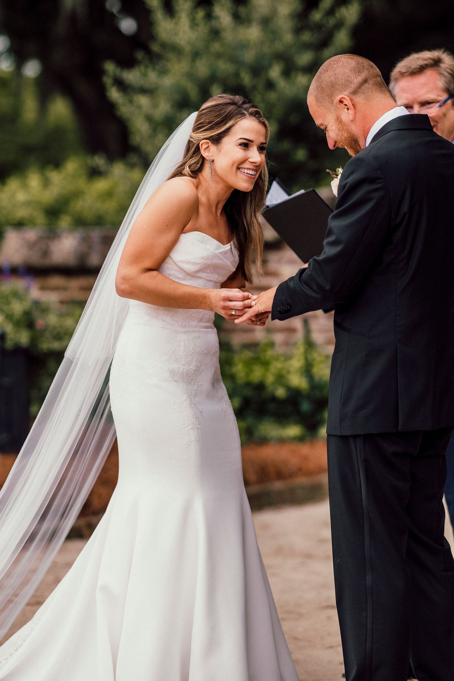 Wedding couple sharing intimate moment in white dress and black suit outdoors.