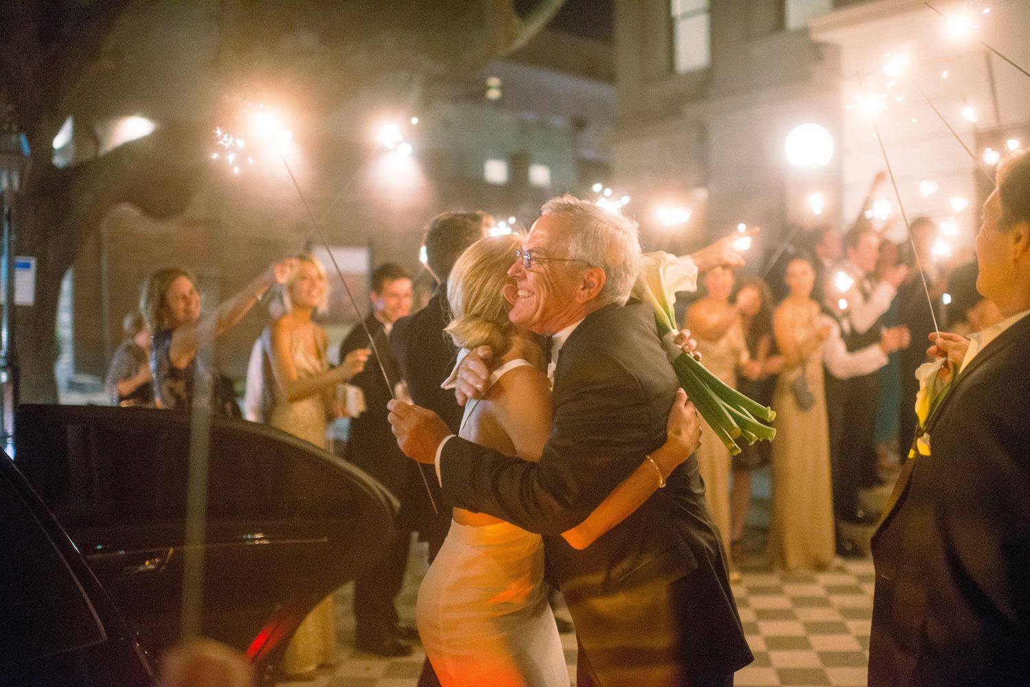 Dancers move together on a dimly lit dance floor with warm orange lighting creating an intimate atmosphere.