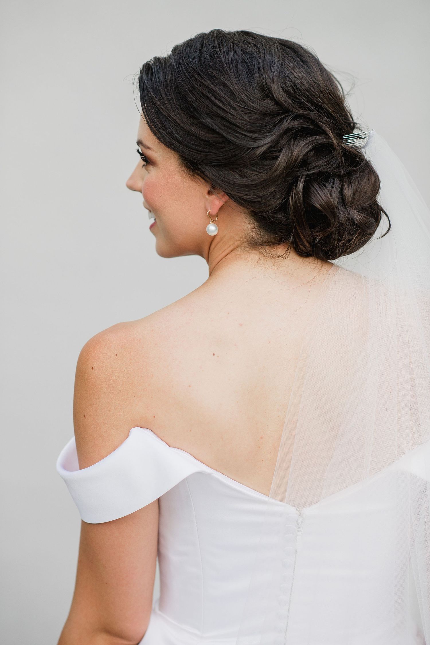 A series of profile shots showing an elegant white off-shoulder wedding dress with delicate details and upswept hairstyle.