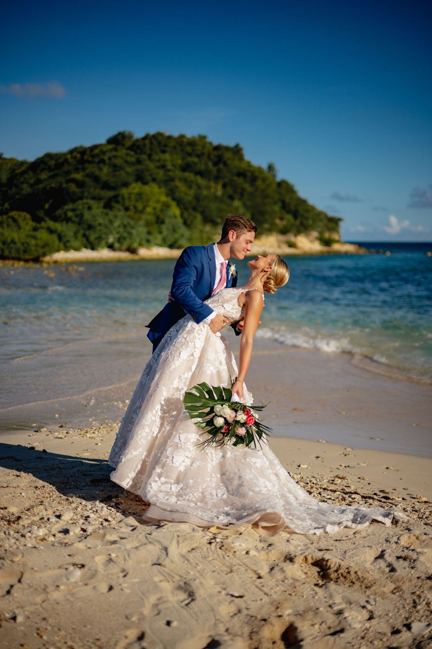 Romantic beach wedding photography session with turquoise ocean and lush island backdrop.