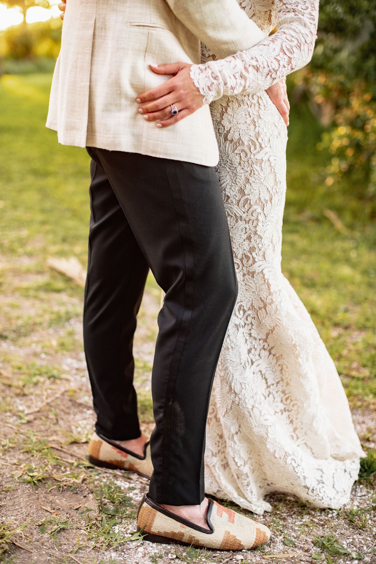 Close-up shots of a couple's feet dancing together, showing white lace dress and black pants against outdoor scenery.