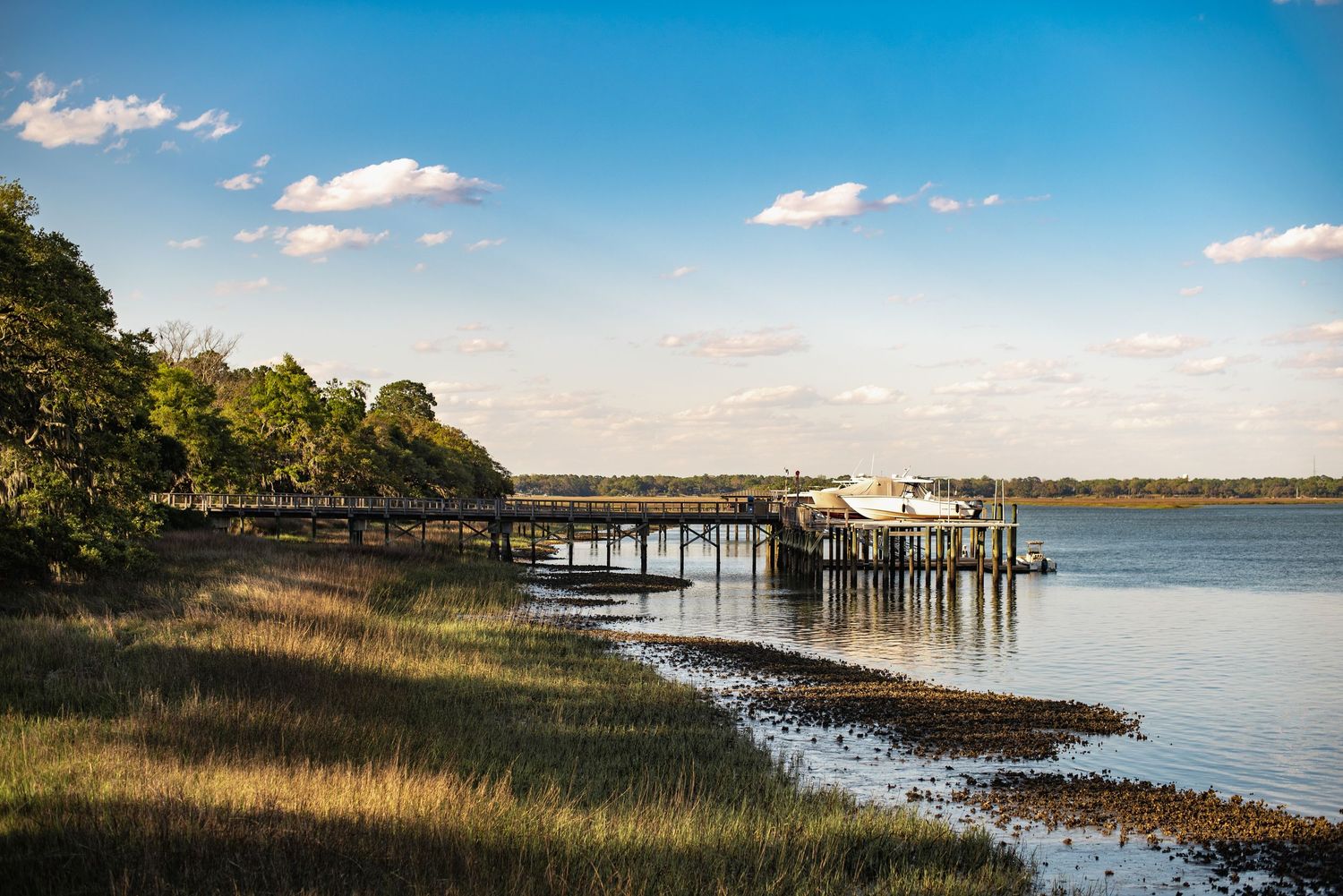 Scenic coastal panorama with wooden docks extending into calm waters under blue sky with scattered clouds.