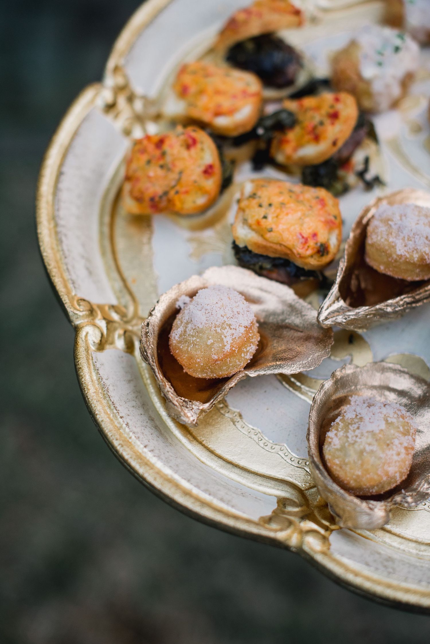 Elegant platter with grilled shrimp appetizers and powdered sugar dusted pastries on a vintage gold-rimmed plate.