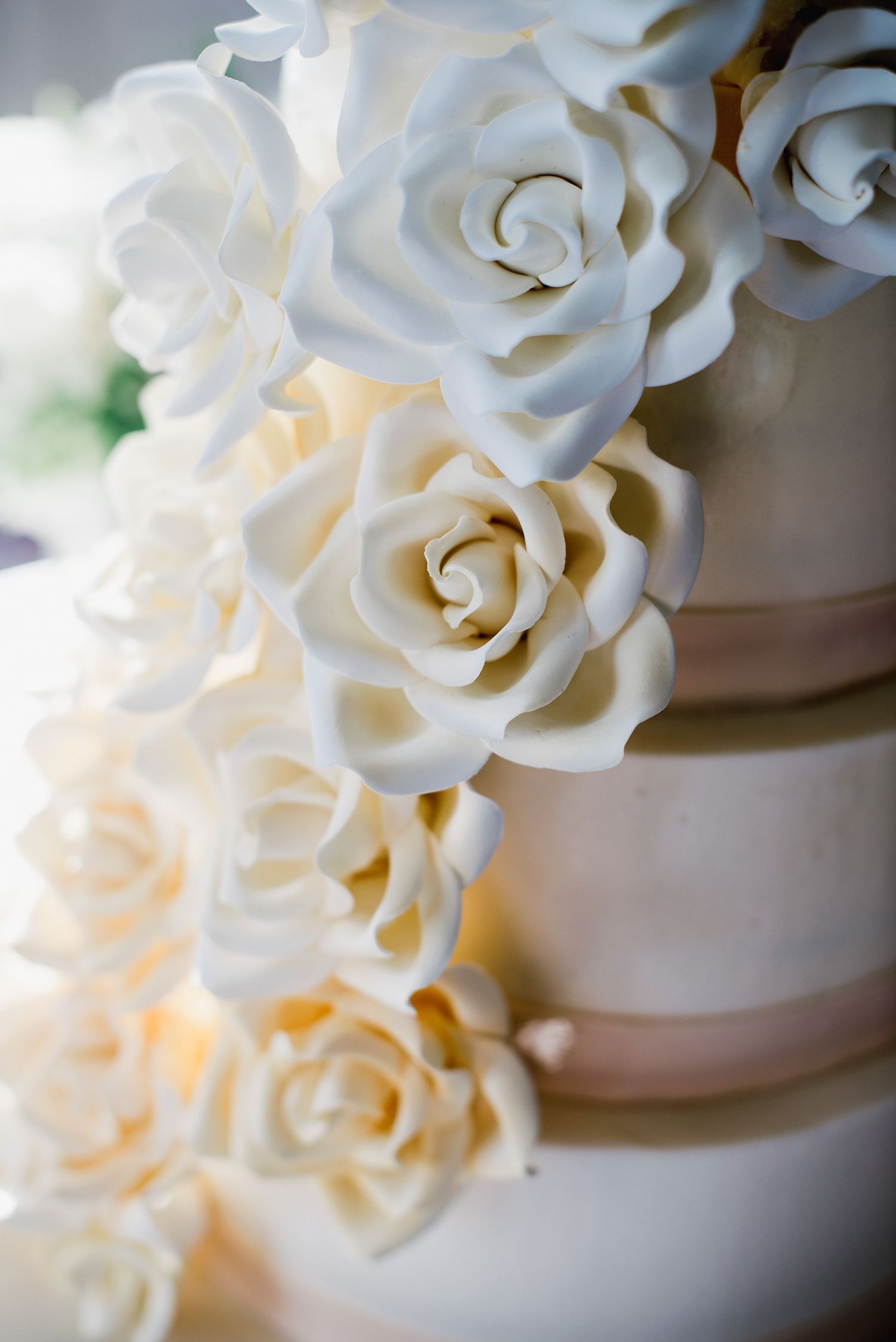 Close-up of elegant white sugar roses decorating tiers of a wedding cake with soft focus effect.