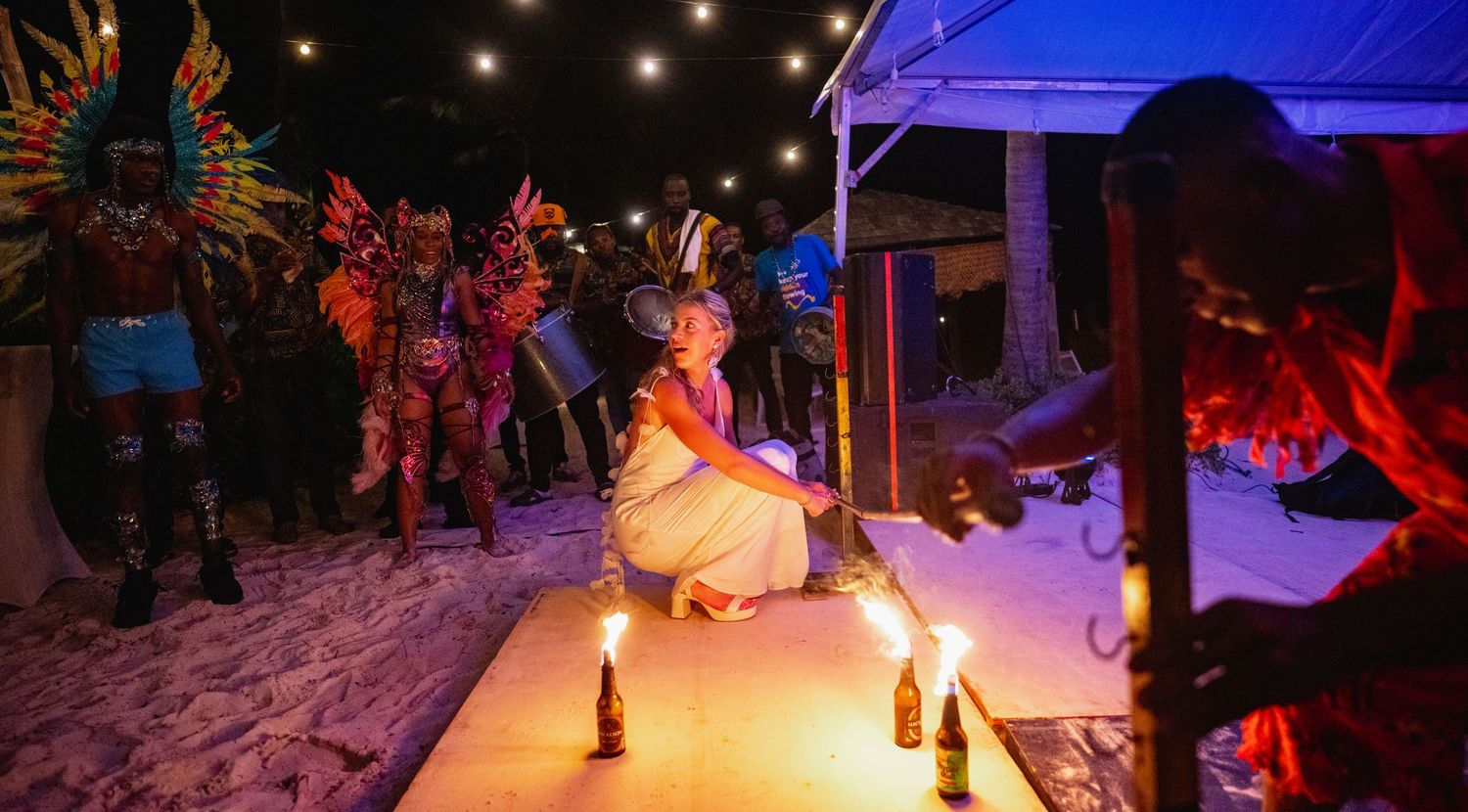 Night beach celebration with string lights and fire performances creating a magical atmosphere.