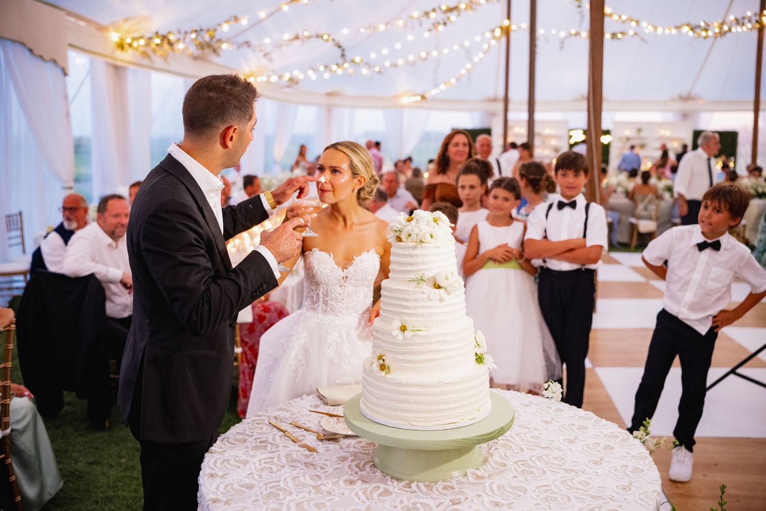 Wedding couple cutting their elegant white tiered cake at their reception celebration.