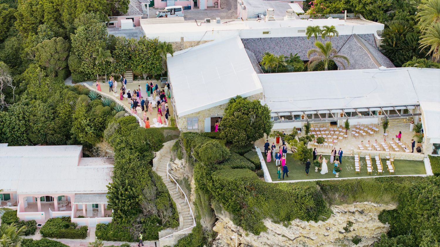 Aerial panoramic view of a wedding venue with white tents, outdoor seating, and lush green landscaping.