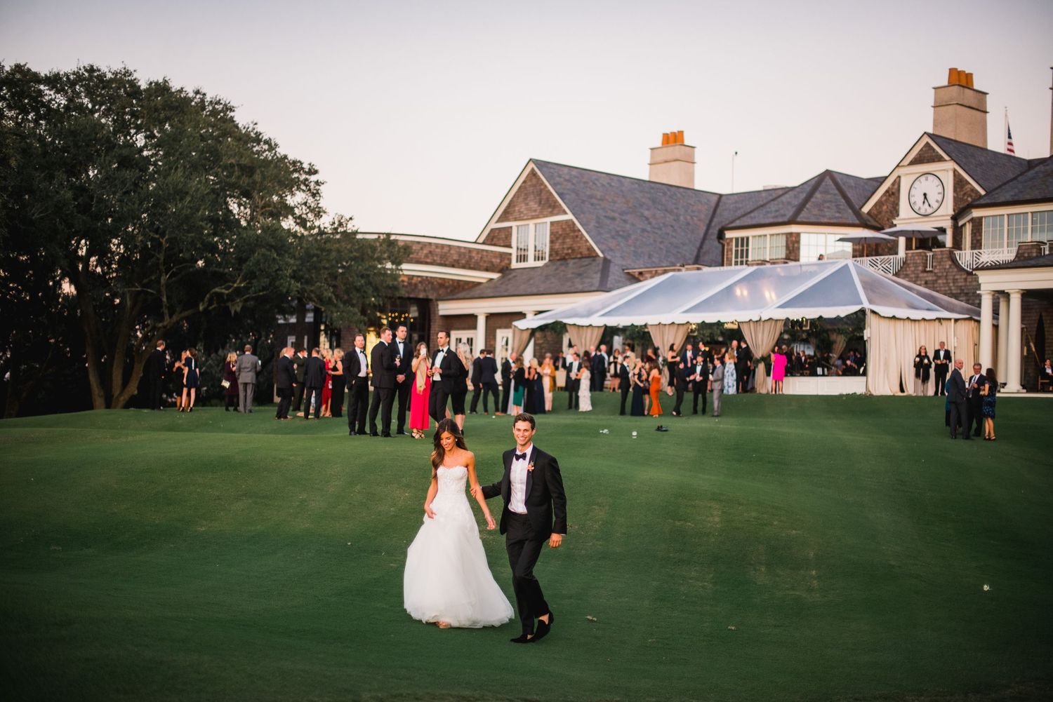 Wedding celebration at dusk on a manicured golf course with guests mingling near a clubhouse.
