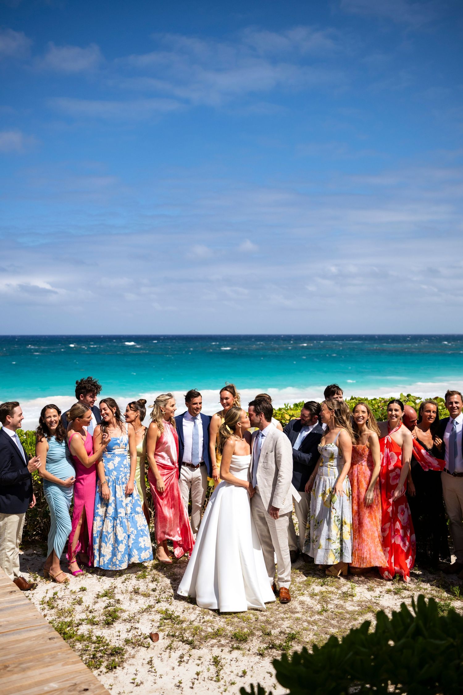 Wedding party gathered in Harbour Island on coastal overlook with bright blue ocean backdrop.