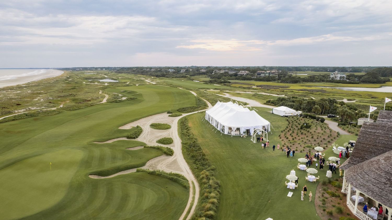 Panoramic aerial view of a coastal golf course with rolling fairways, sand bunkers, and clubhouse facilities.