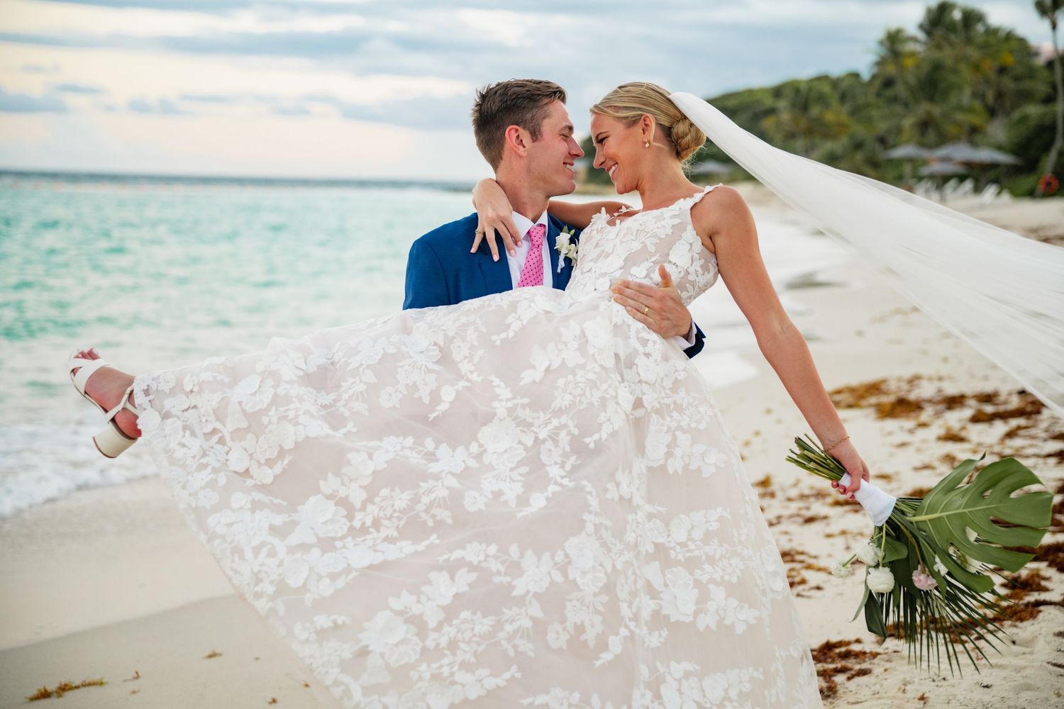 Romantic beach wedding portraits with flowing white dress against tropical scenery.