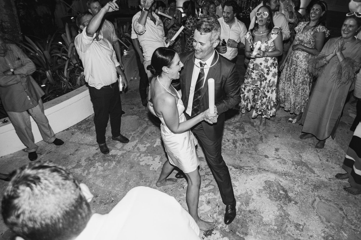 Wedding guests dance and celebrate on a confetti-covered dance floor during a lively reception party.