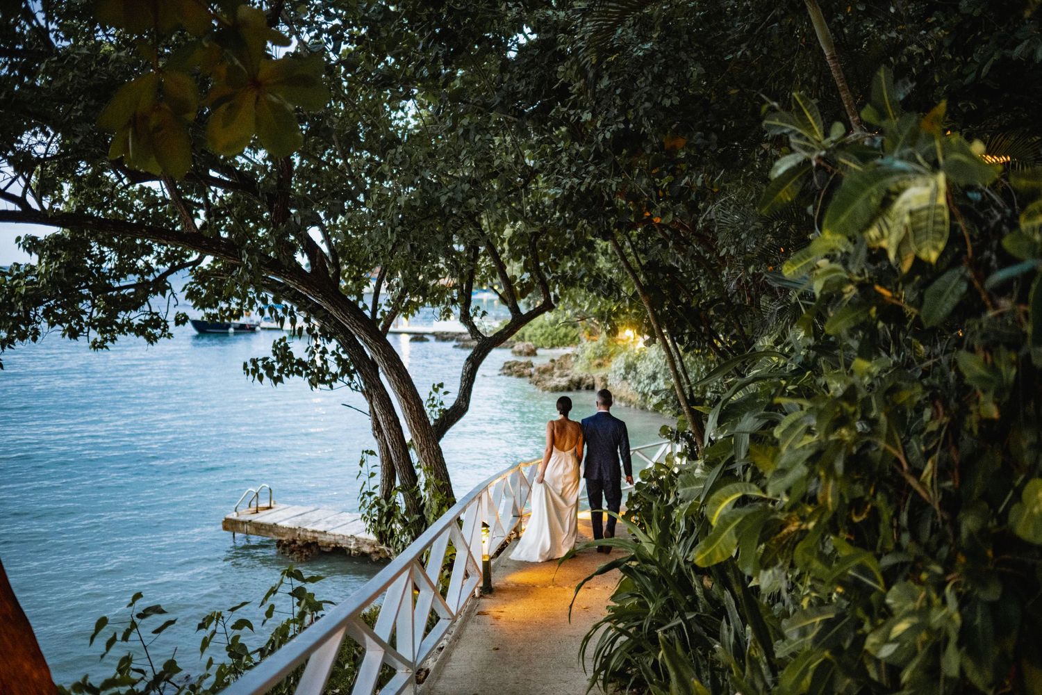 Tropical resort pathway leading to overwater bungalows and ocean views through lush greenery in the Maldives.