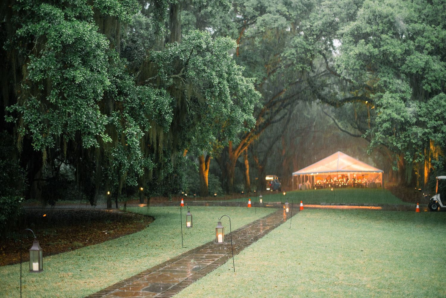 A scenic path through a lush green park with trees and a small wooden structure visible in the distance.