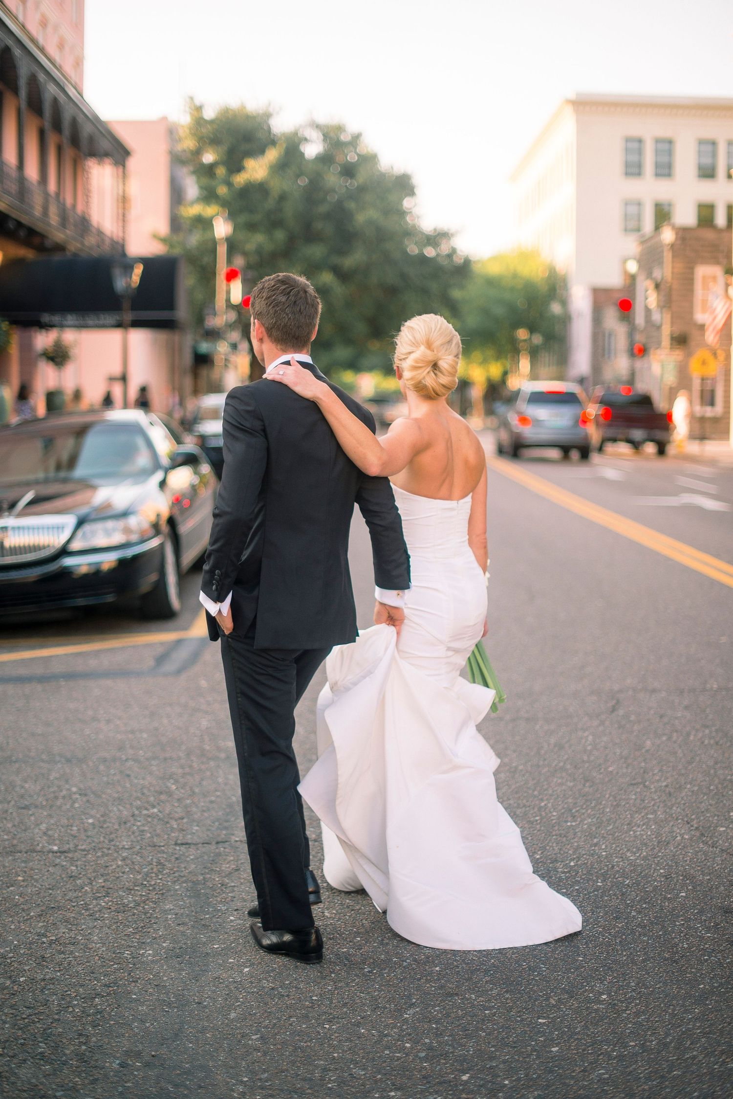 A couple in wedding attire walks together down an urban street at sunset in a series of candid moments.