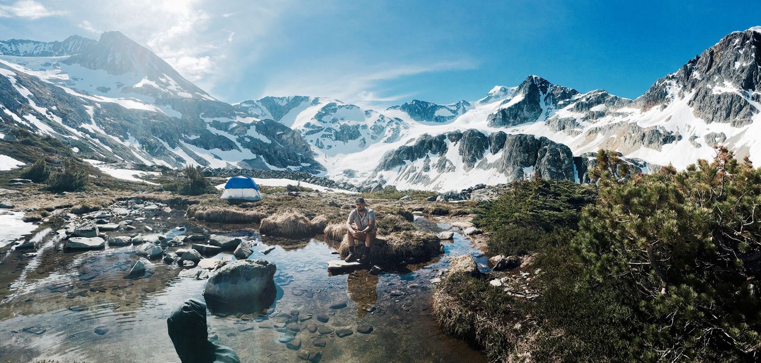 Dramatic mountain panorama showing snow-capped peaks and glacial valleys in bright sunlight.