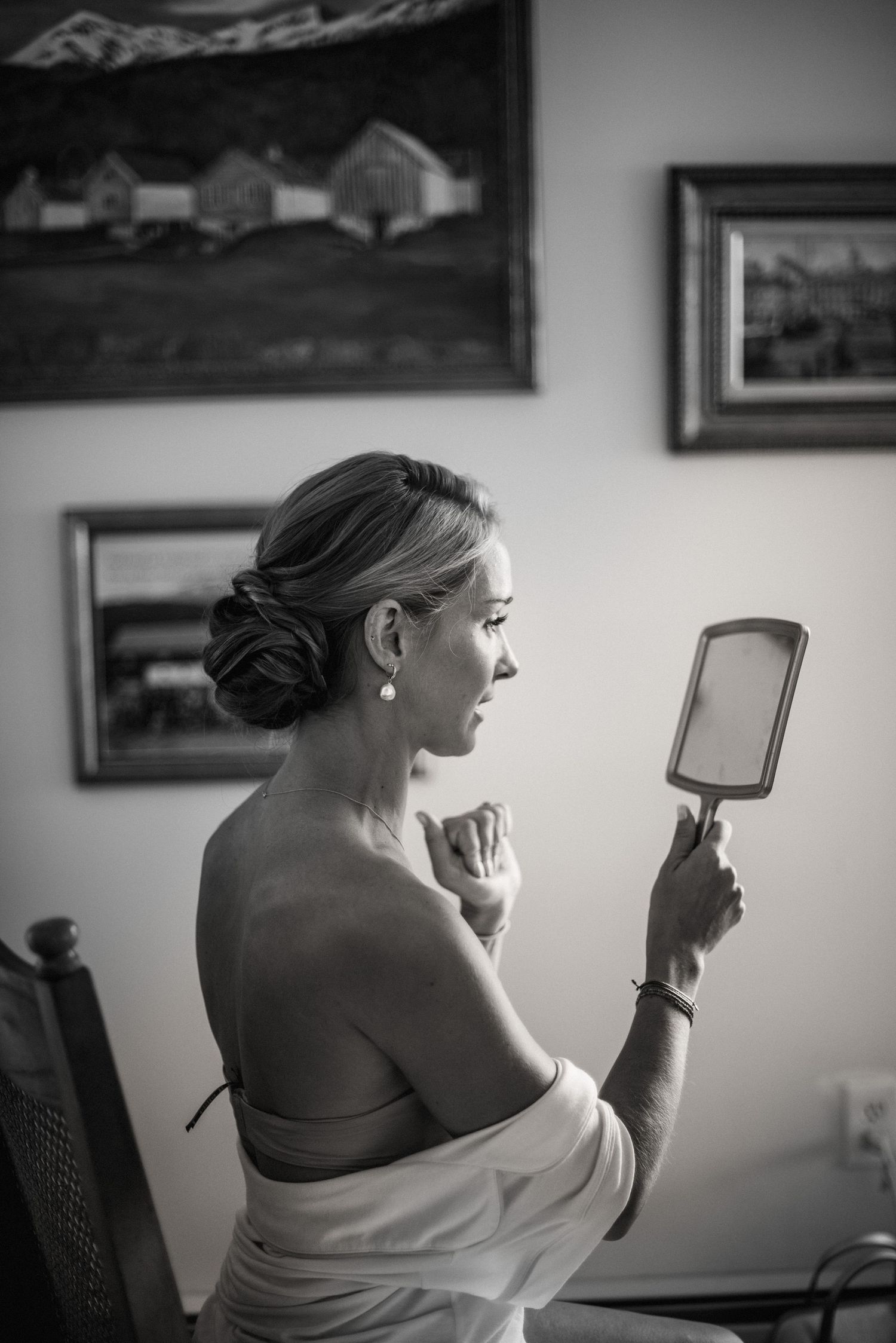 A series of black and white photos showing a person applying makeup while looking in a handheld mirror.