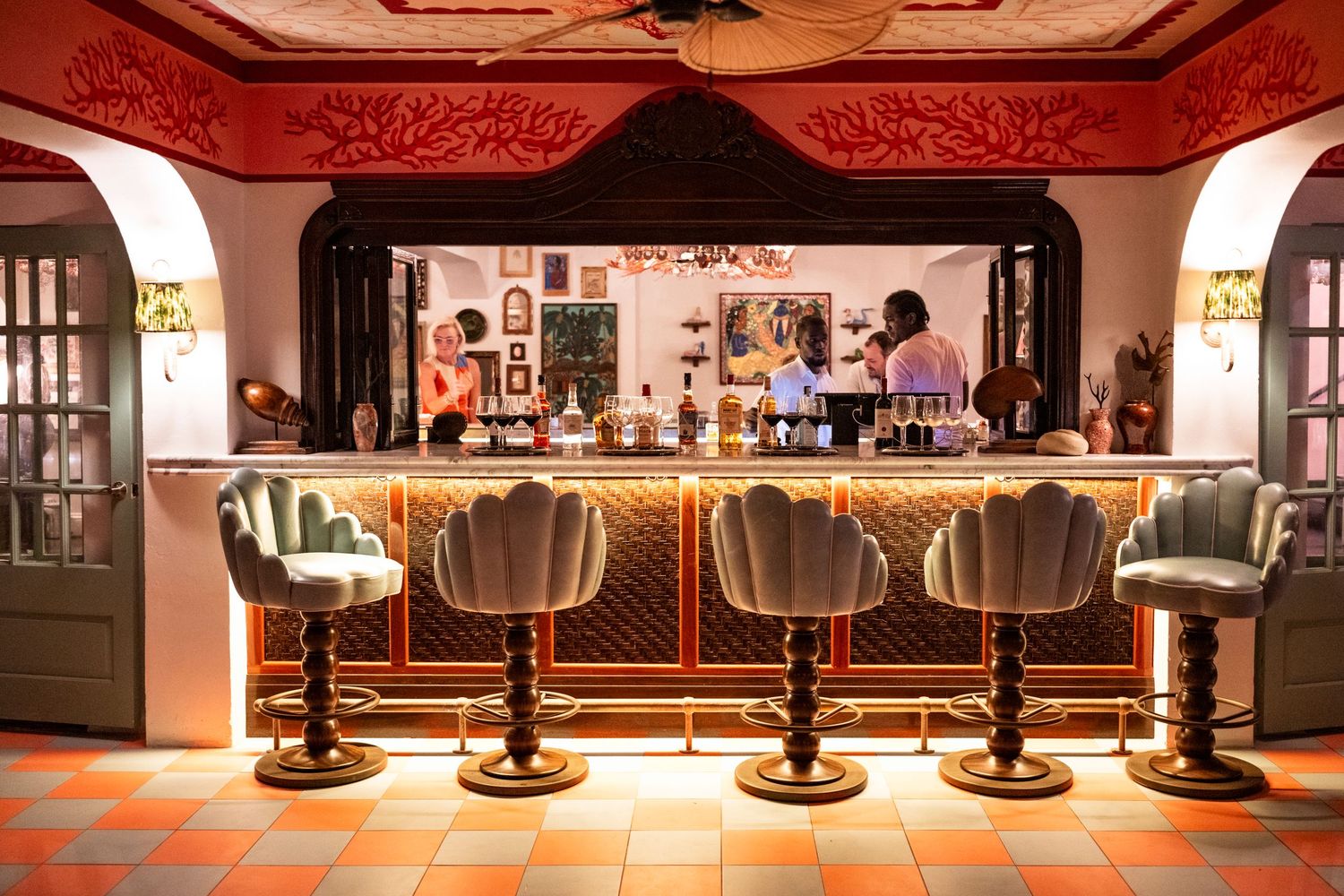 Elegant bar interior of Coral Sands club Bahamas with ornate red ceiling and multiple bar stools lined up in a row.