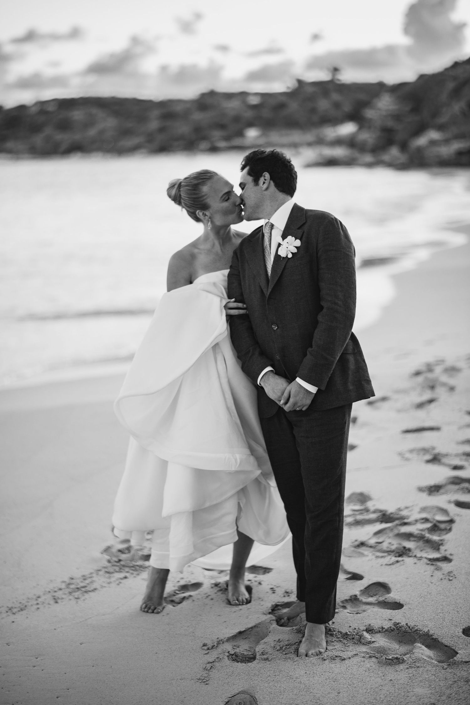 Romantic couple shares intimate moments on a sandy beach during their wedding photoshoot.
